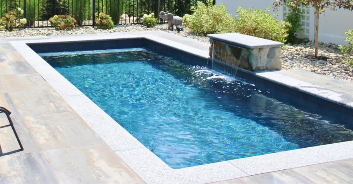 Clean rectangular backyard pool with a stone water feature